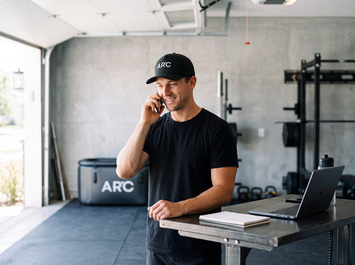 An ARC team member on a call in a garage gym, with an ARC tub behind them